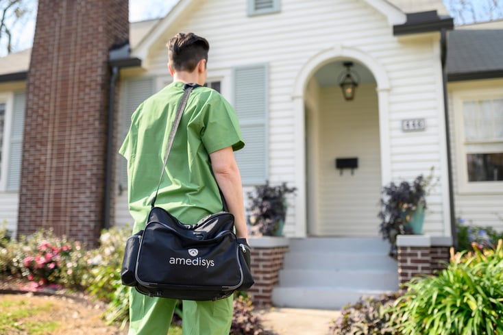 nurse with medical bag walking up to a house