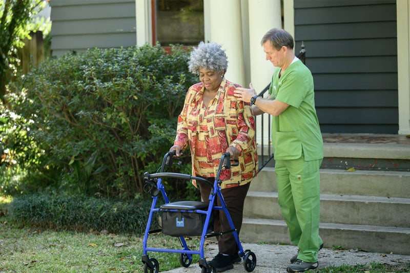 Nurse helping home health patient walk down the stairs. 