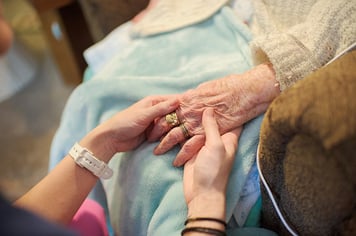 Hospice patient and caregiver holding hands