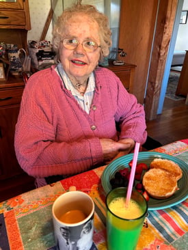 Elderly woman seated at a table with breakfast