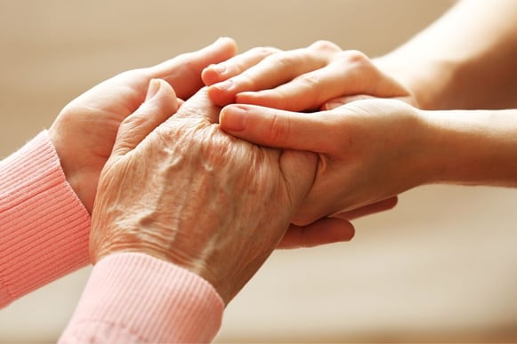 Two hands holding two elderly hands in comfort