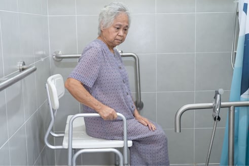 Elderly woman sits on a shower chair