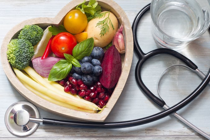 stethescope next to bowl of fruits and vegetables