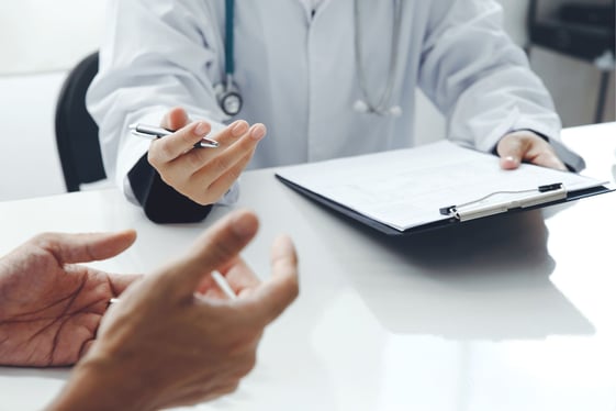 Doctor taking notes during discussion with patient
