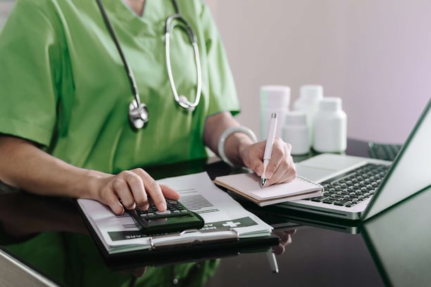 clinician with calculator making notes