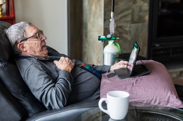 Man using oxygen while resting with a tablet and coffee