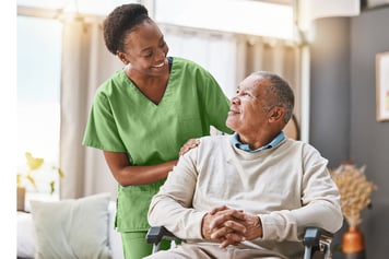 nurse in green scrubs smiling at older patient