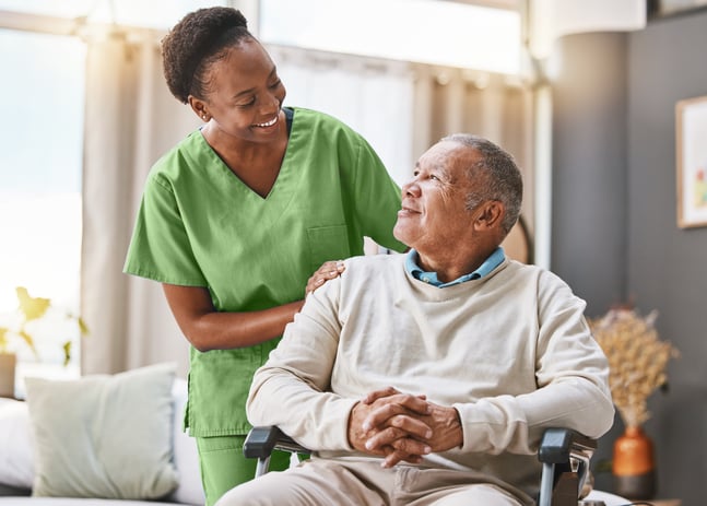 Nurse in green scrubs with smiling patient at home