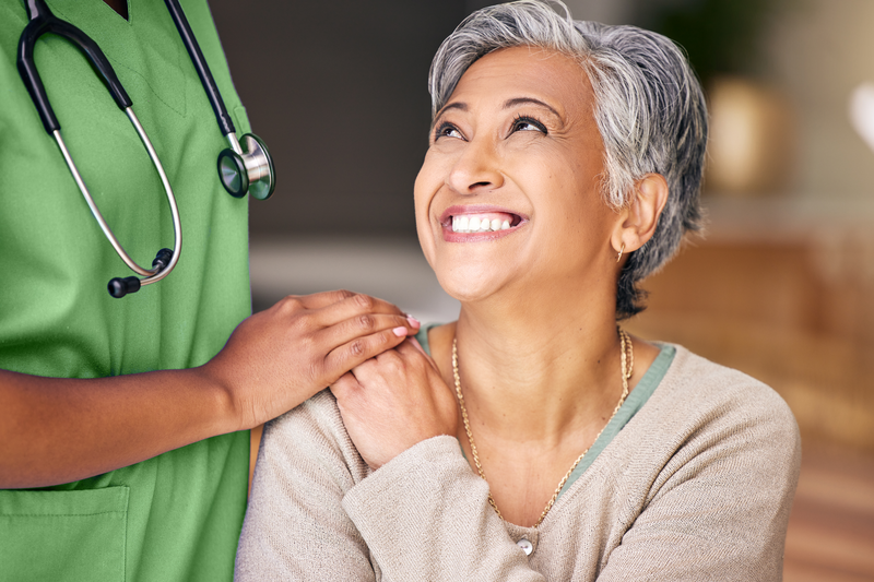 elderly woman smiling and nurse's hand on her shoulder