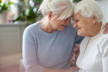Elderly woman receiving hug from daughter